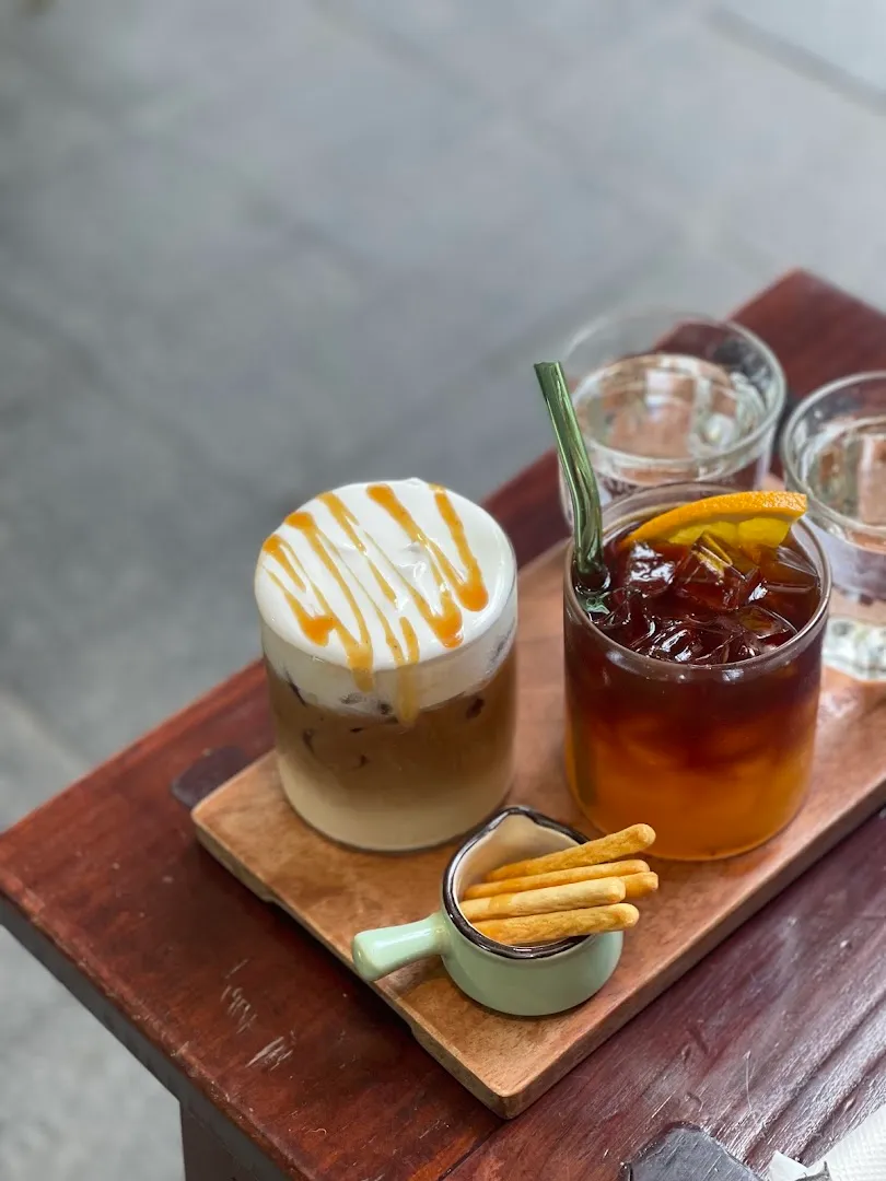 Khung đồ uống gồm cà phê kem caramel và trà cam lạnh dùng kèm bánh que.
