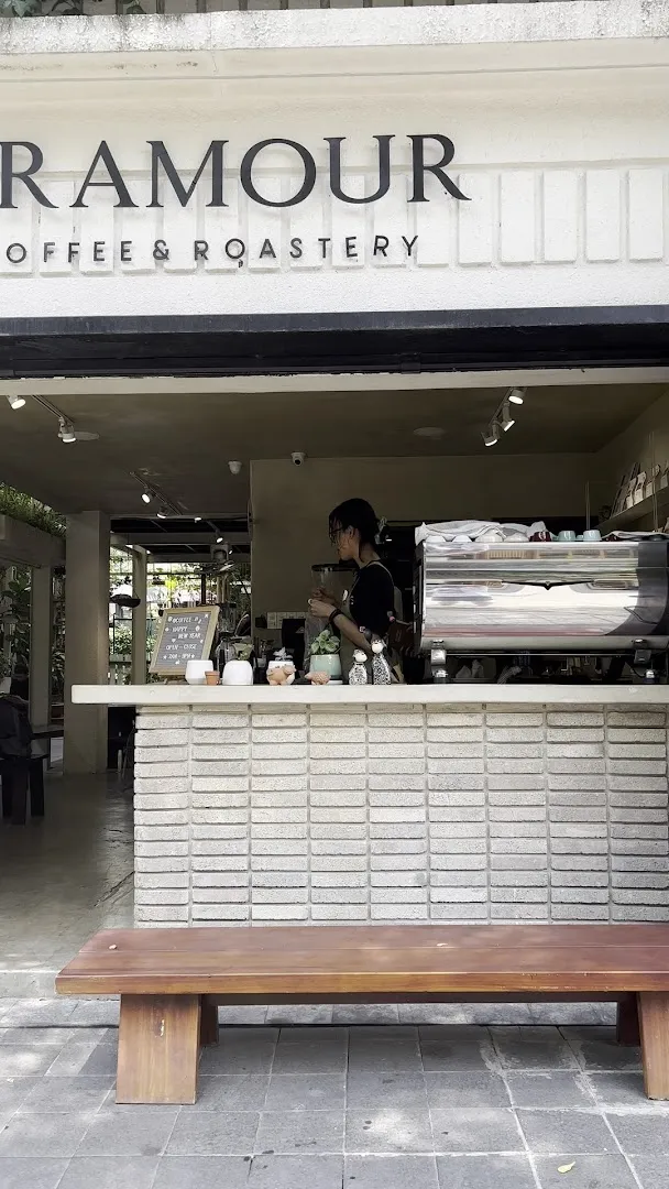 Mặt tiền Aramour Coffee & Roastery với quầy pha chế và ghế băng phía trước.