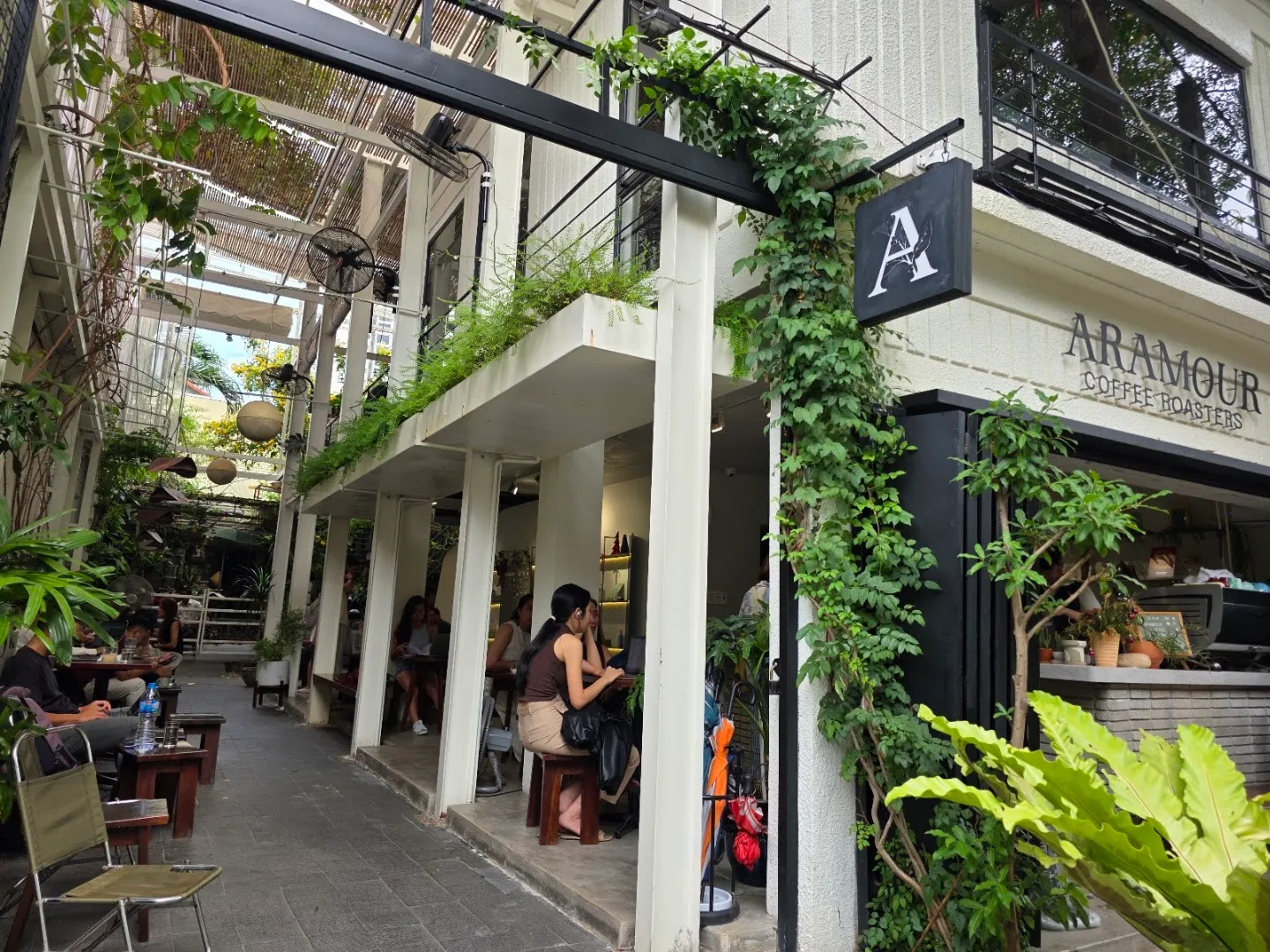 Mặt tiền xanh mát và không gian chỗ ngồi của Aramour Coffee Roasters.