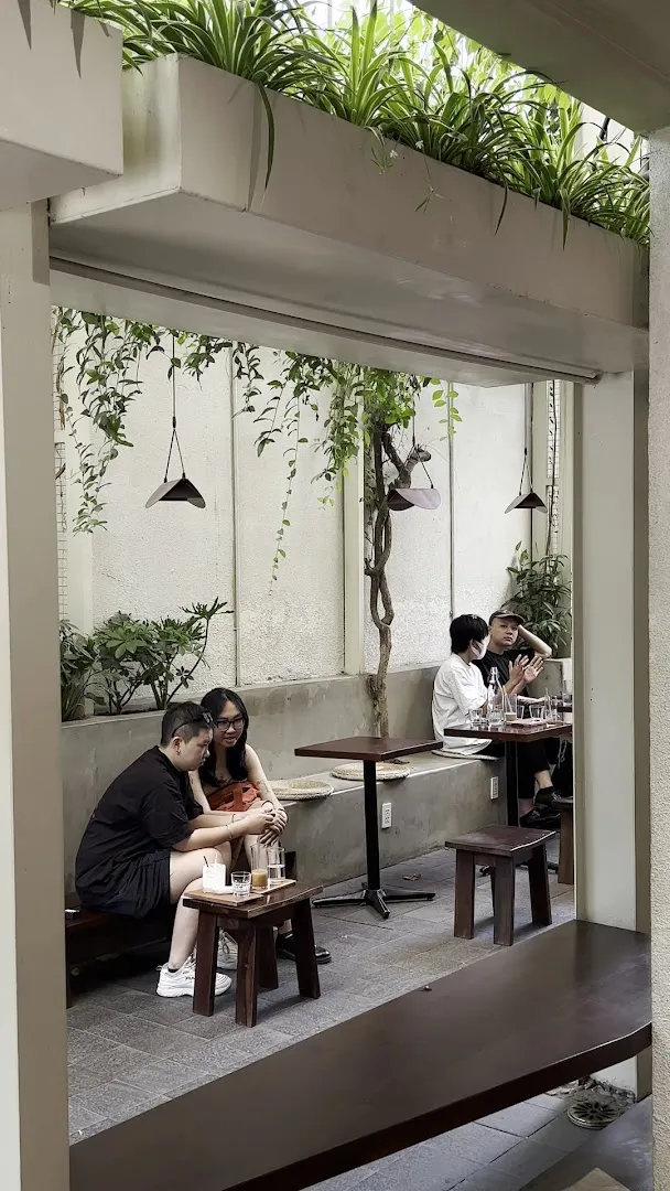 Không gian sân trong thoáng đãng với bàn ghế và cây xanh.