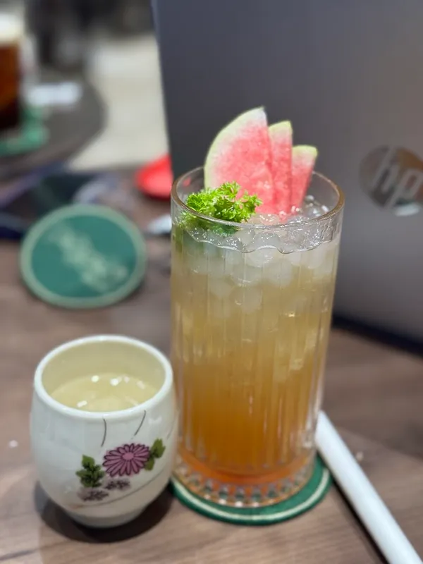 Ly đồ uống lạnh trang trí lát dưa hấu và rau mùi trên bàn cà phê.