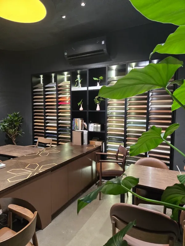 Không gian quán với bàn ghế gỗ, kệ trang trí và nhiều cây xanh.