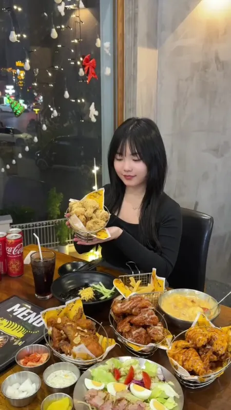 Khách thưởng thức các món gà chiên, khoai tây và salad tại bàn trong nhà hàng.