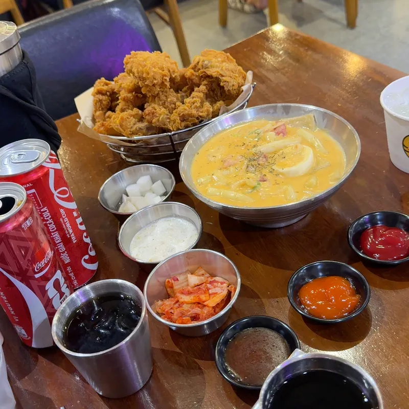 Gà chiên giòn, món ăn kèm, nước sốt và đồ uống được bày trên bàn.
