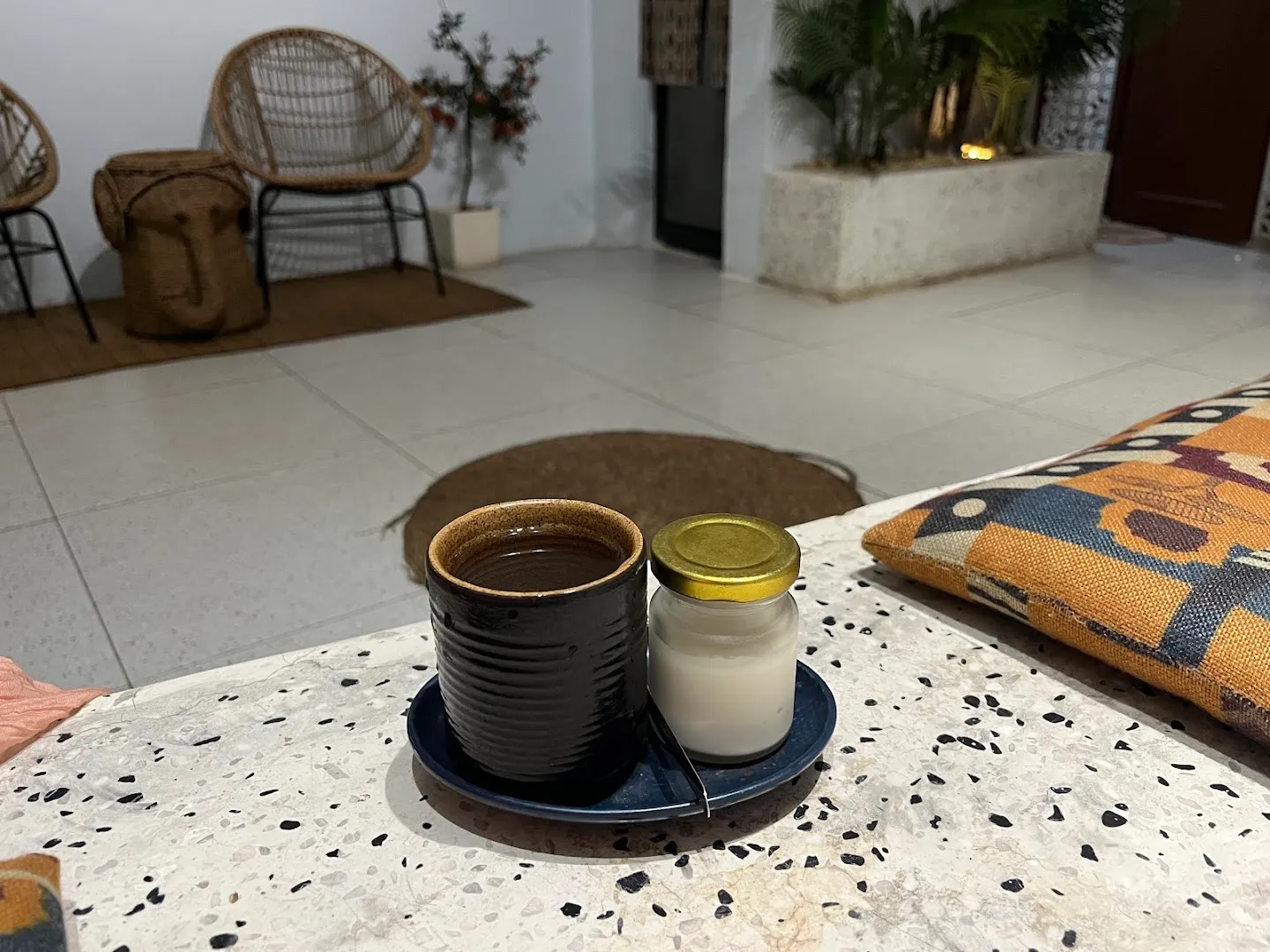 Không gian thư giãn với bàn trà, ghế mây và cây xanh.