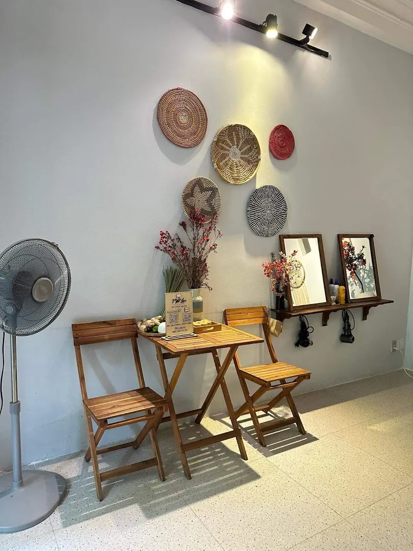 Góc tiếp khách với bàn ghế gỗ và tranh đan lát trang trí trên tường.
