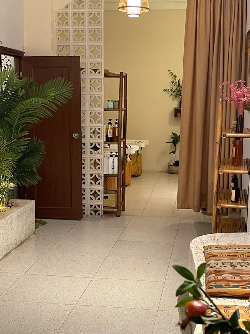 Không gian spa ấm cúng với rèm riêng tư, kệ sản phẩm chăm sóc và cây xanh.