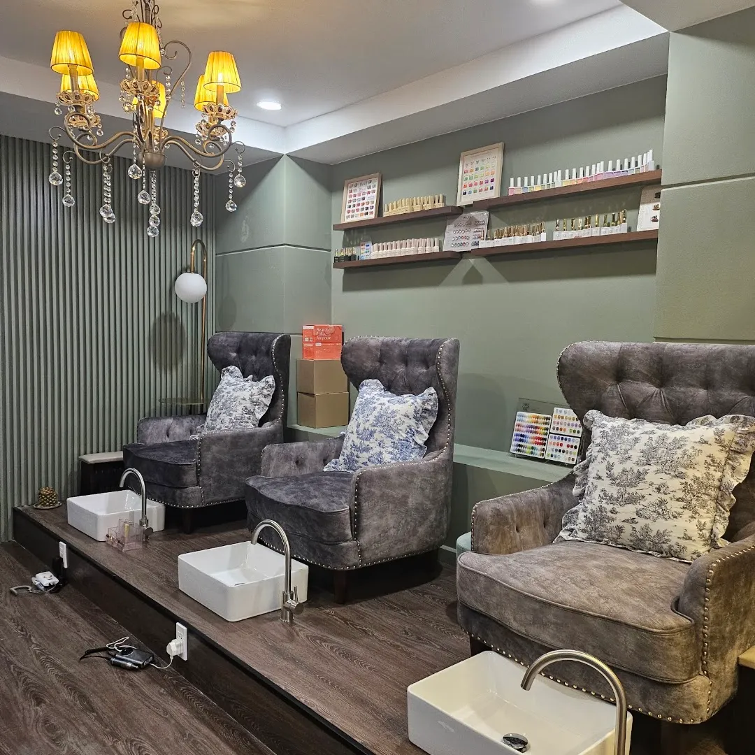 Không gian spa với các ghế chăm sóc chân, bồn rửa và kệ sản phẩm làm đẹp.