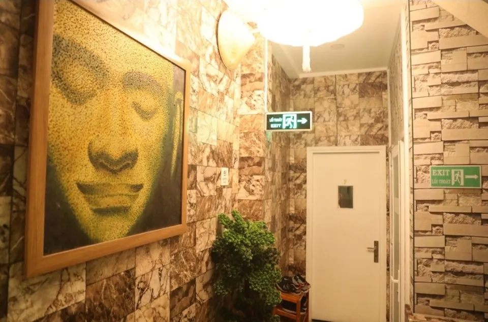 Hành lang spa với tranh Phật, tường đá trang trí và cửa phòng.