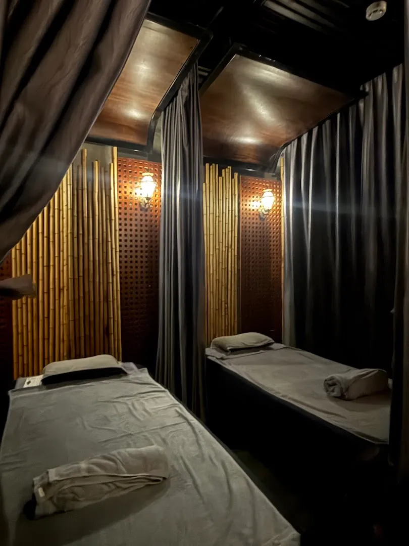 Phòng massage riêng với hai giường trị liệu, rèm che và ánh sáng ấm áp.