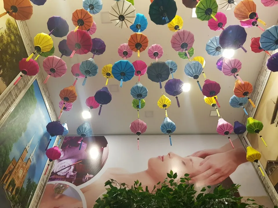 Trần phòng spa trang trí nhiều ô lọng giấy cùng tranh minh họa massage.