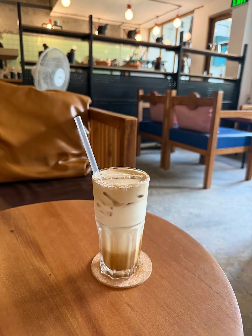 Ly cà phê sữa đá trên bàn trong không gian quán ấm cúng.