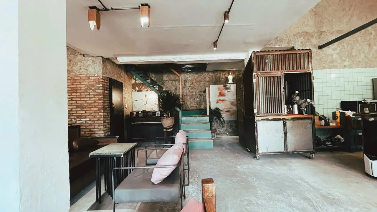 Không gian quán cà phê với khu vực ghế ngồi, bàn nhỏ và quầy pha chế.