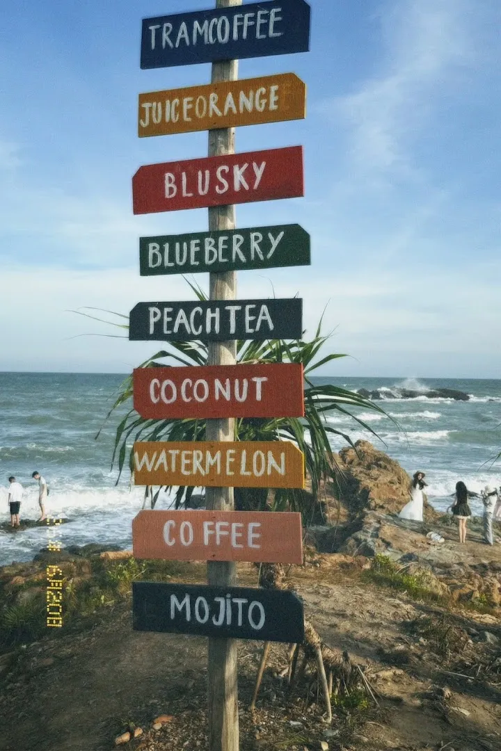 Biển chỉ dẫn các loại đồ uống như nước ép cam, trà đào, cà phê và mojito bên bờ biển.