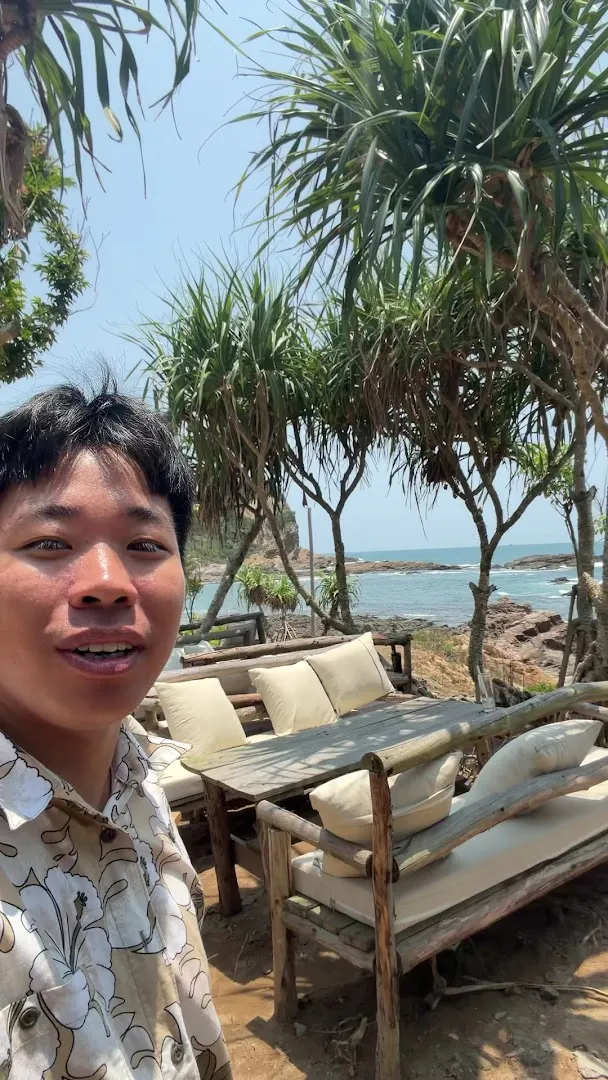 Không gian ghế ngồi ngoài trời bên bờ biển, dưới những hàng cây nhiệt đới.