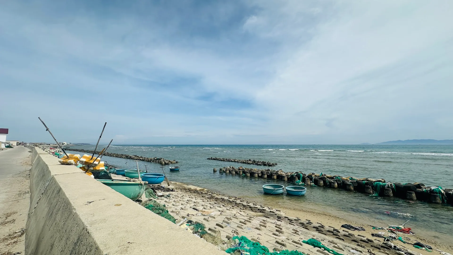Cảnh bờ biển với thuyền thúng và đê chắn sóng