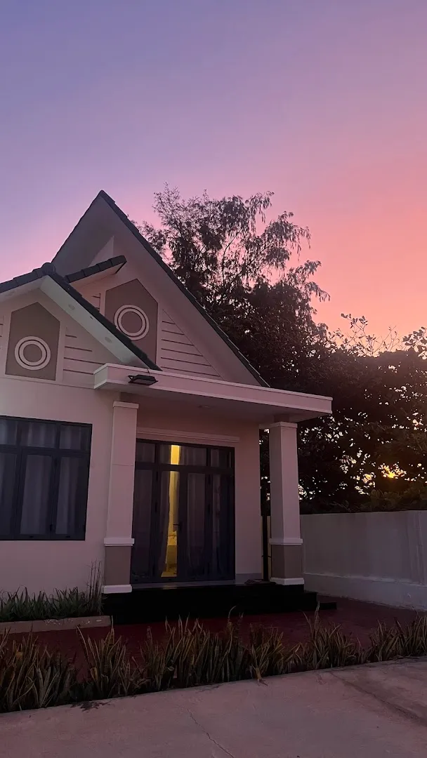 Mặt tiền ngôi nhà với lối vào và khoảng sân phía trước lúc hoàng hôn.
