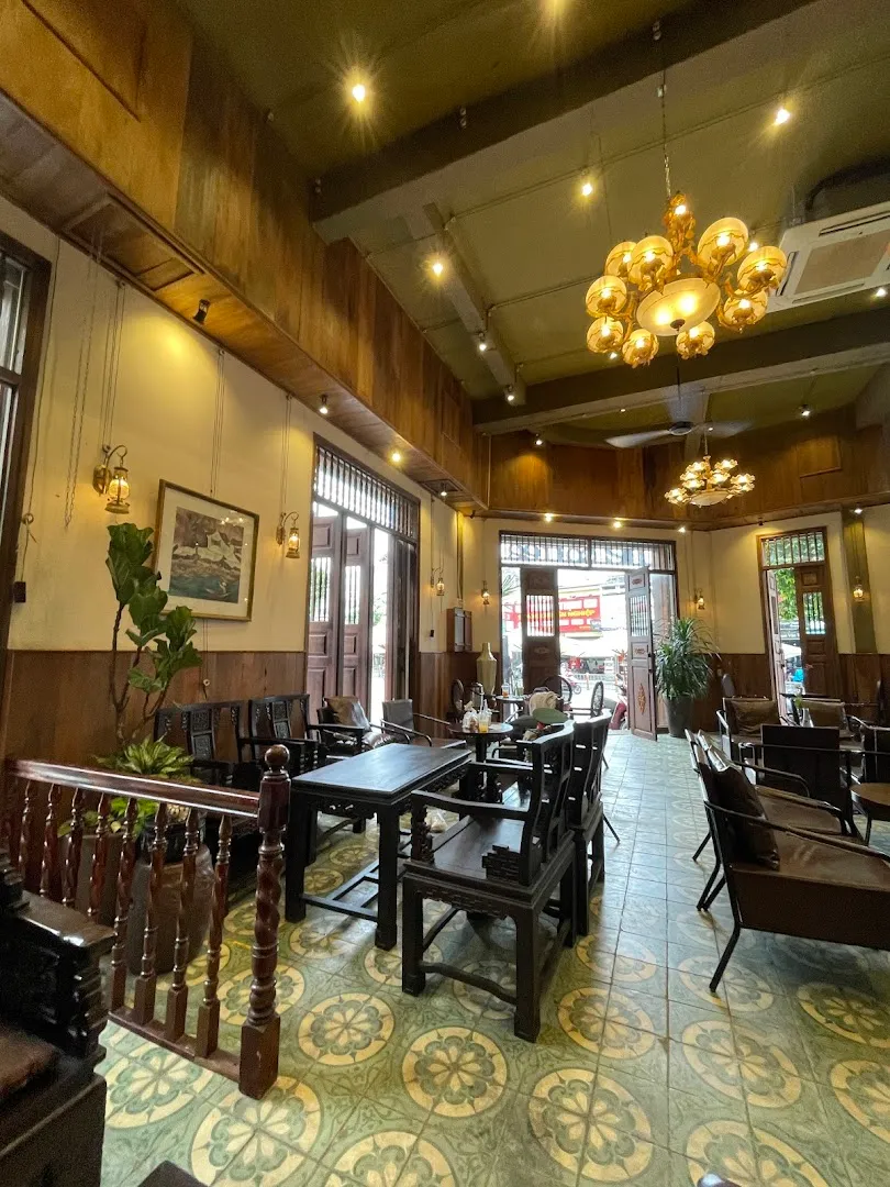 Không gian bên trong quán với bàn ghế gỗ, đèn chùm và sàn gạch hoa cổ điển.