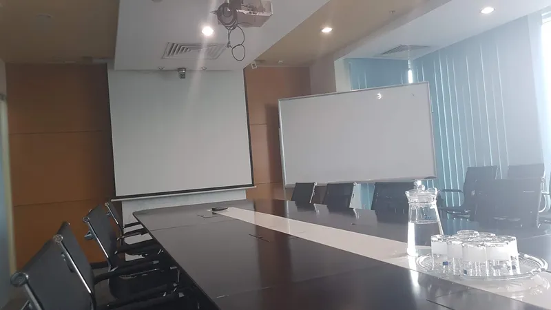 Phòng họp với bàn hội nghị, ghế ngồi và màn hình trình chiếu.