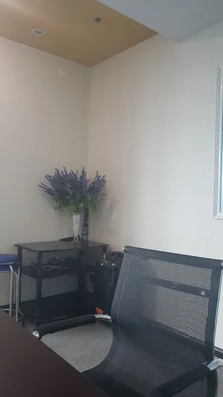 Góc phòng làm việc với bàn, ghế và lọ hoa trang trí.