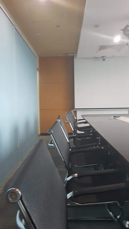 Phòng họp với bàn dài, ghế ngồi và màn chiếu.