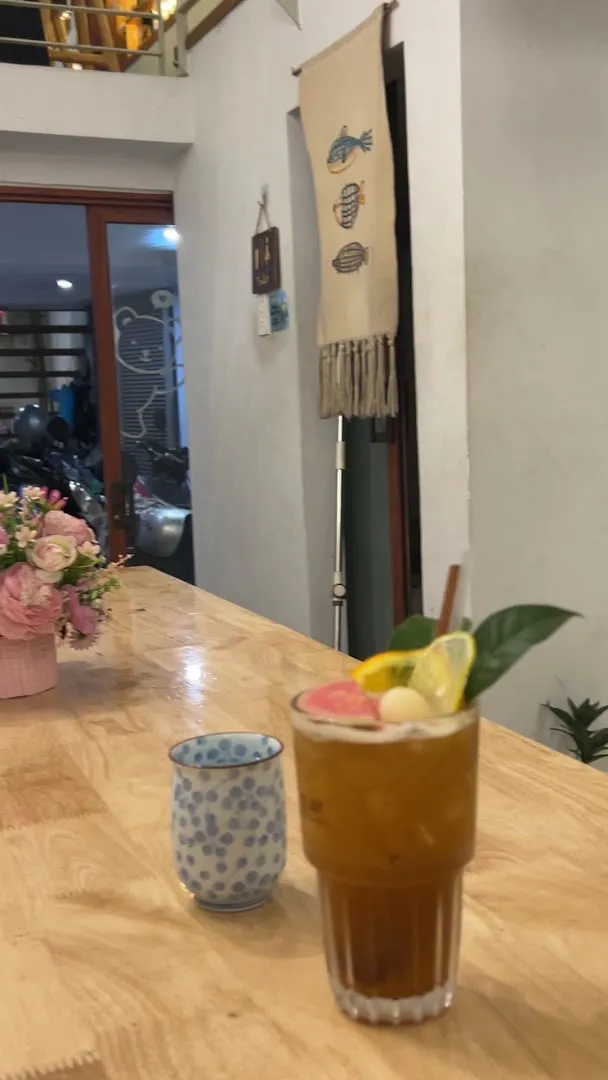 Ly đồ uống trang trí lát trái cây trên bàn gỗ trong không gian quán.