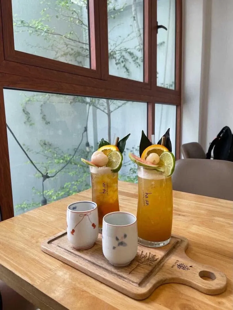 Hai ly đồ uống cam chanh trang trí trái cây trên khay gỗ tại quán cà phê.