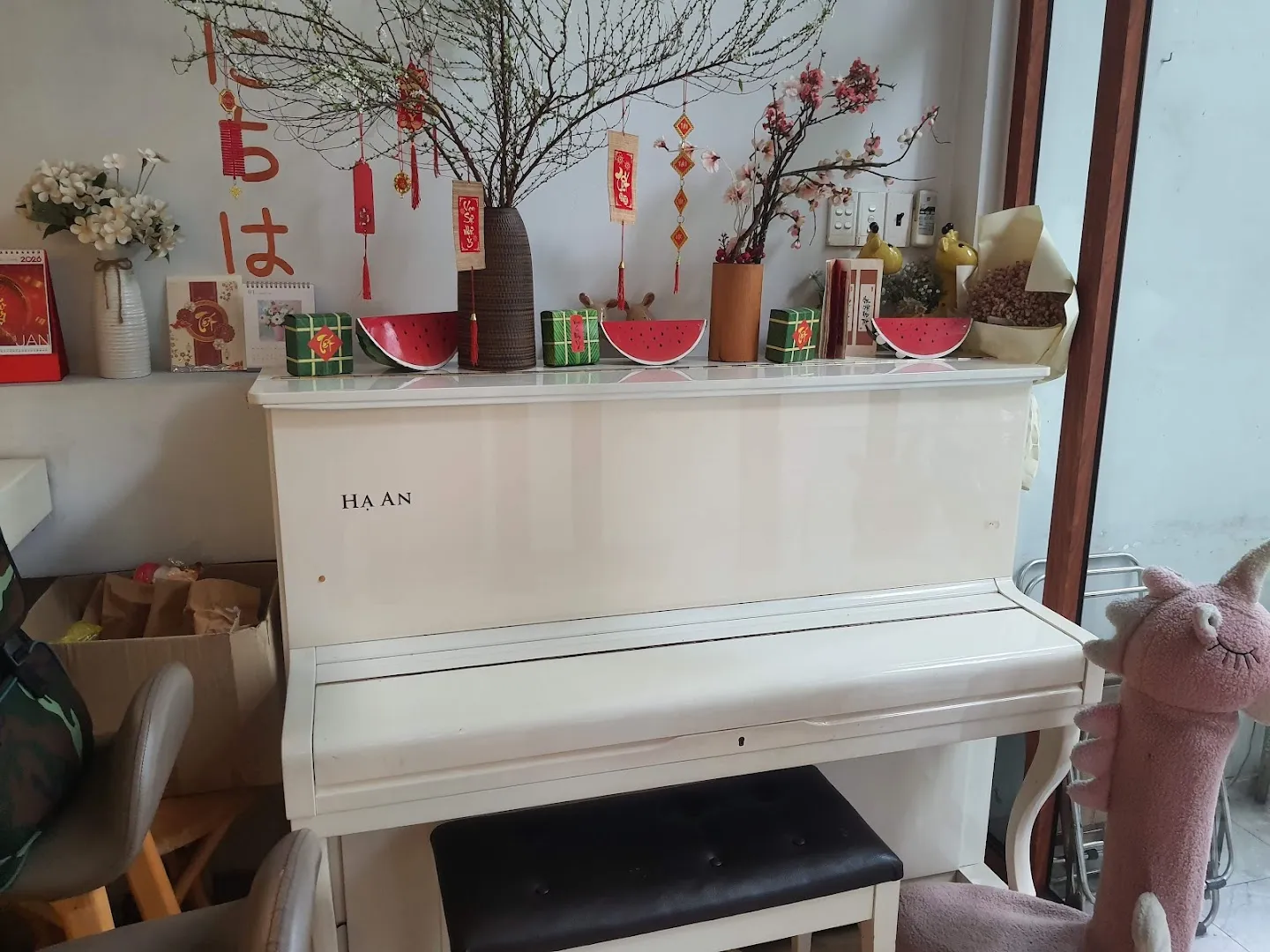 Đàn piano trắng mang tên HẠ AN, trang trí hoa và phụ kiện Tết trong không gian quán.
