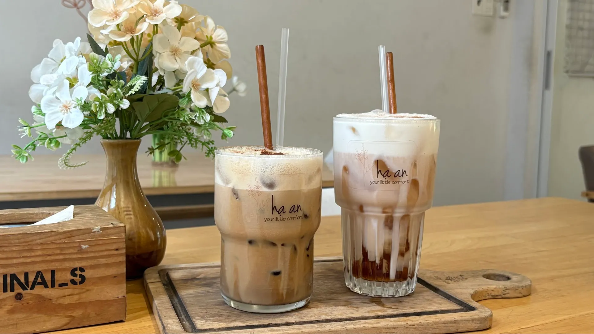 Hai ly cà phê sữa đá trên bàn gỗ, in logo Ha An.