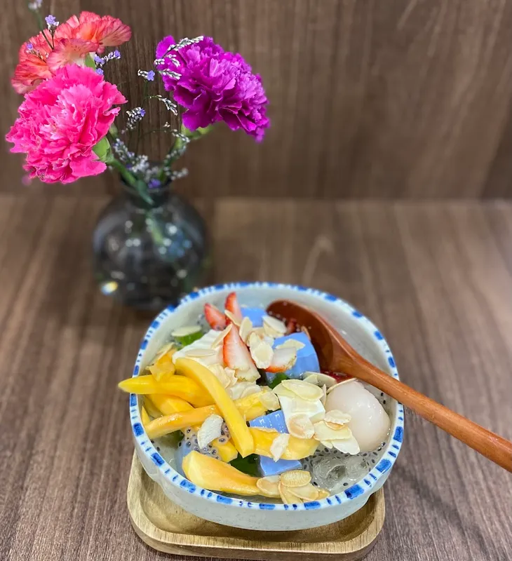 Bát chè trái cây nhiều màu sắc, trang trí cùng hoa tươi.