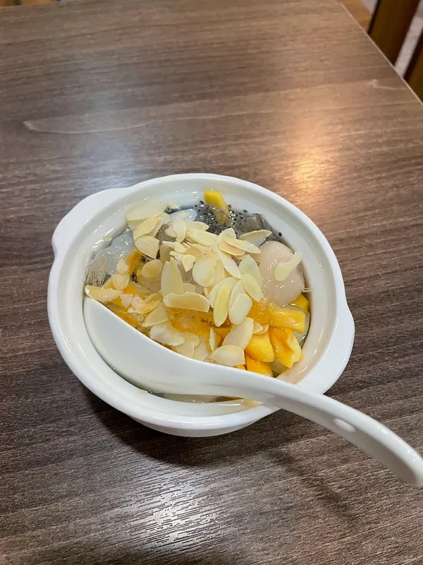 Chè trái cây với hạnh nhân lát trong bát sứ trắng.