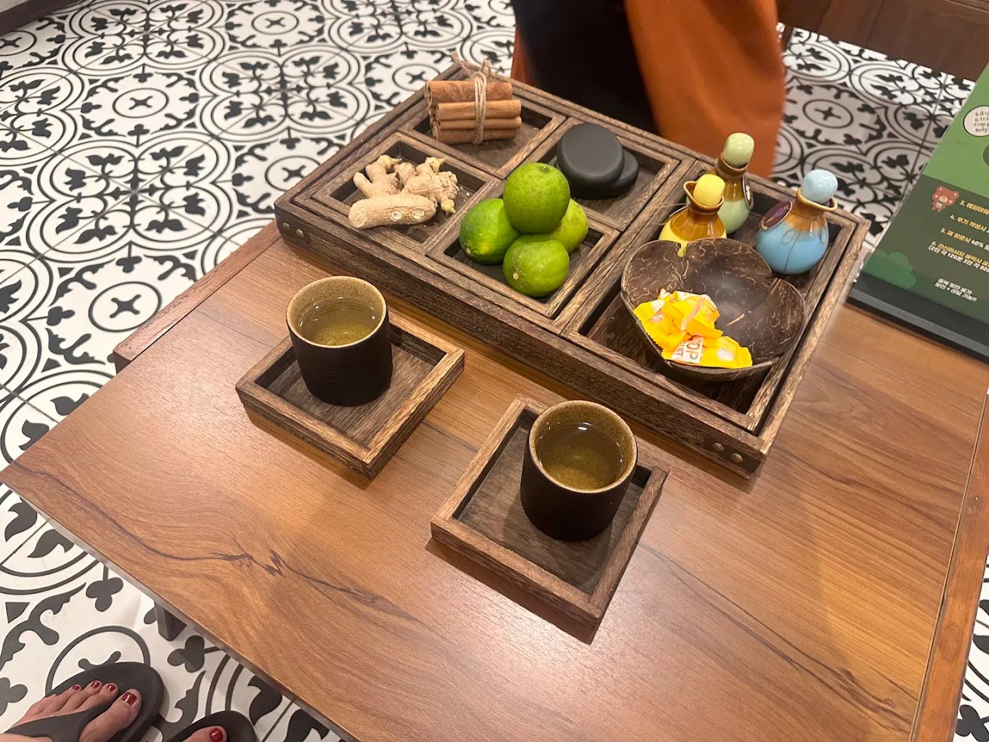 Bàn trà với trà thảo mộc, gừng, chanh xanh và các lọ tinh dầu trong không gian spa.