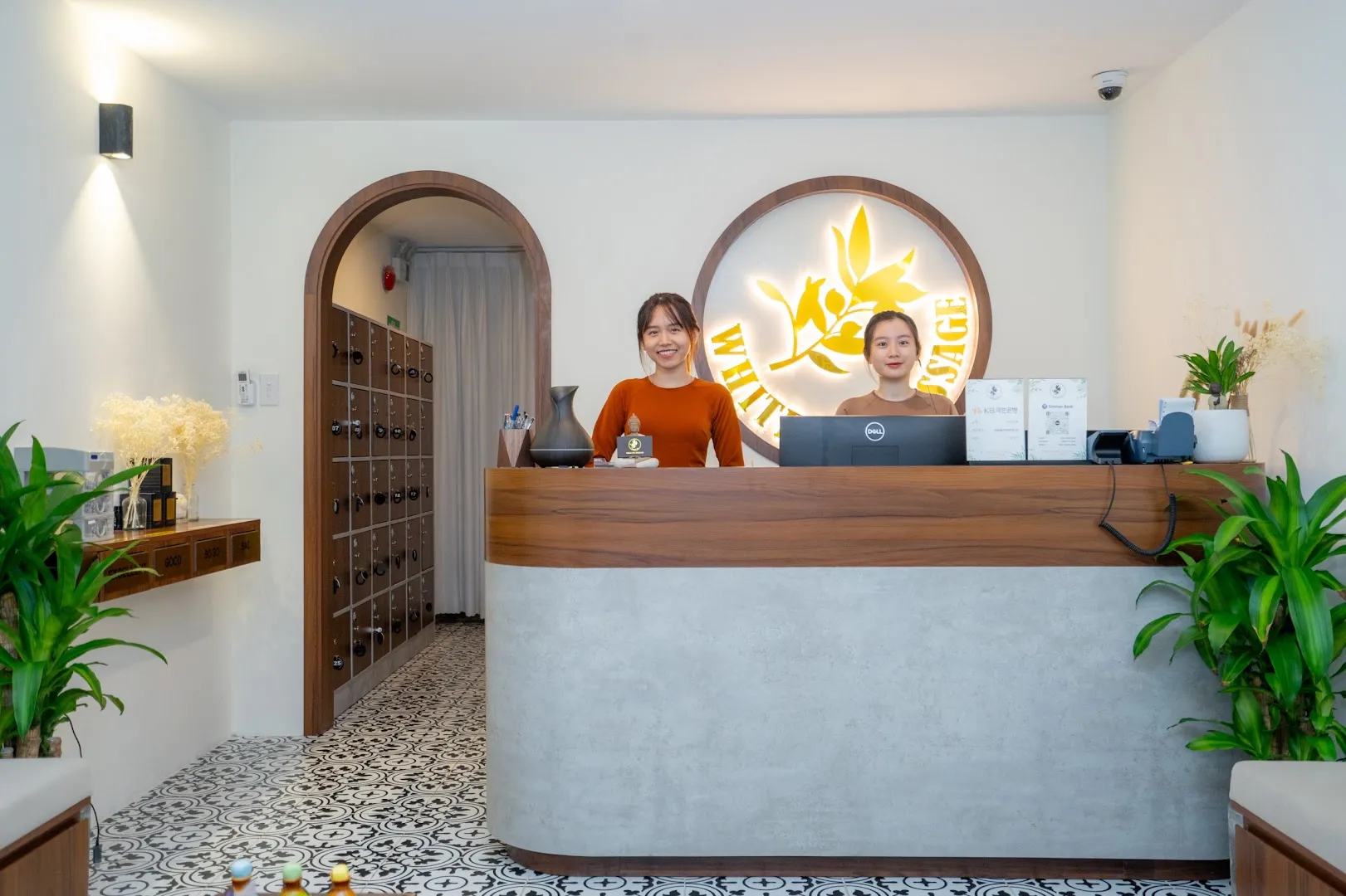 Quầy lễ tân spa với nhân viên và khu vực tủ khóa phía sau.