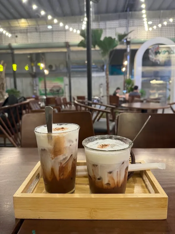 Hai ly cà phê sữa đá dùng tại quán, đặt trên khay gỗ.