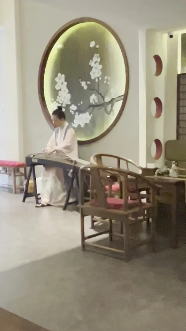 Không gian nội thất với bàn ghế gỗ và tranh hoa mai trang trí.