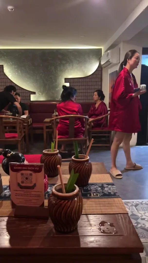 Không gian sảnh thư giãn với bàn ghế gỗ, cây xanh trang trí và nhân viên phục vụ.