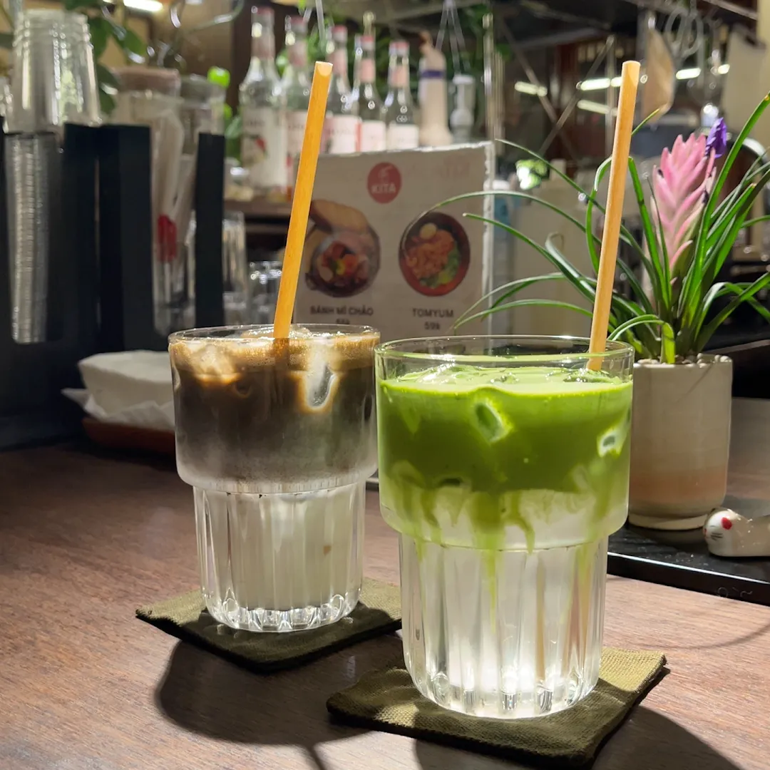 Hai ly đồ uống gồm cà phê đá và thức uống matcha xanh trên bàn quán.