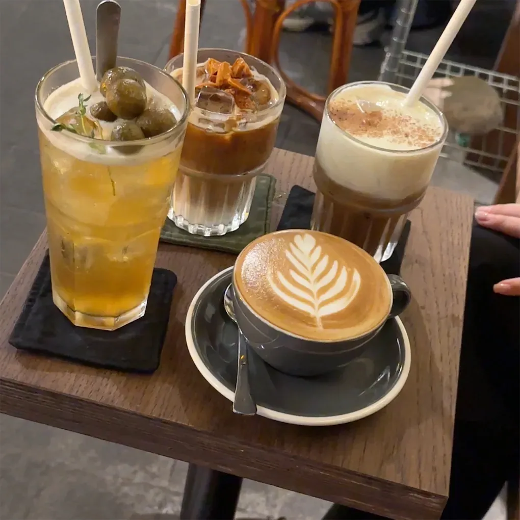 Các món đồ uống gồm cà phê latte, cà phê đá và đồ uống trái cây trên bàn.