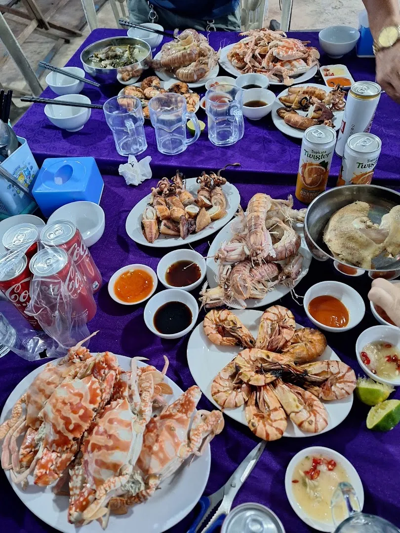 Bàn tiệc hải sản với cua, tôm, mực và các loại nước chấm.