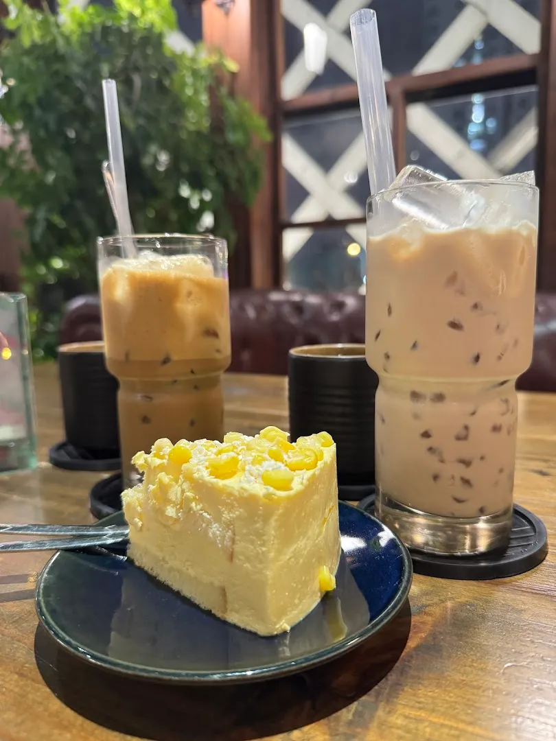 Hai ly đồ uống đá và một phần bánh kem bắp trên bàn cà phê.