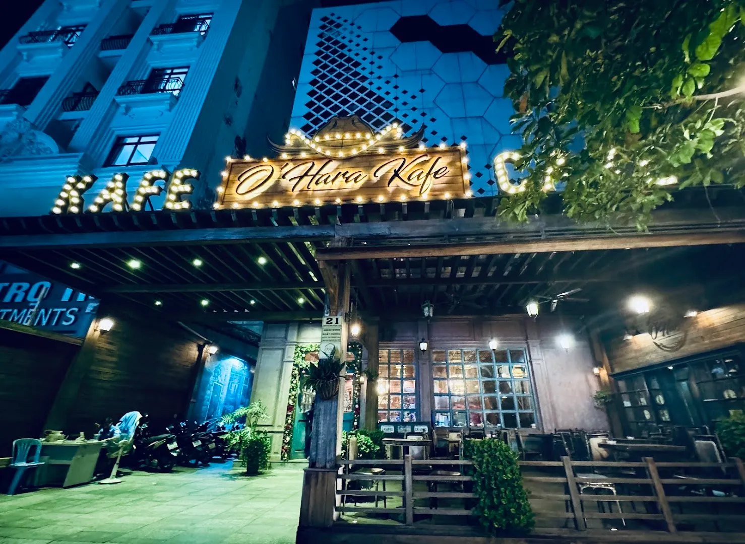 Mặt tiền O’Hara Kafe với bảng hiệu phát sáng và khu vực chỗ ngồi ngoài trời vào buổi tối.