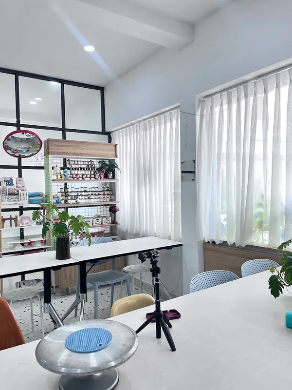 Không gian lớp học làm bánh với bàn thực hành, ghế ngồi và kệ dụng cụ trang trí bánh.