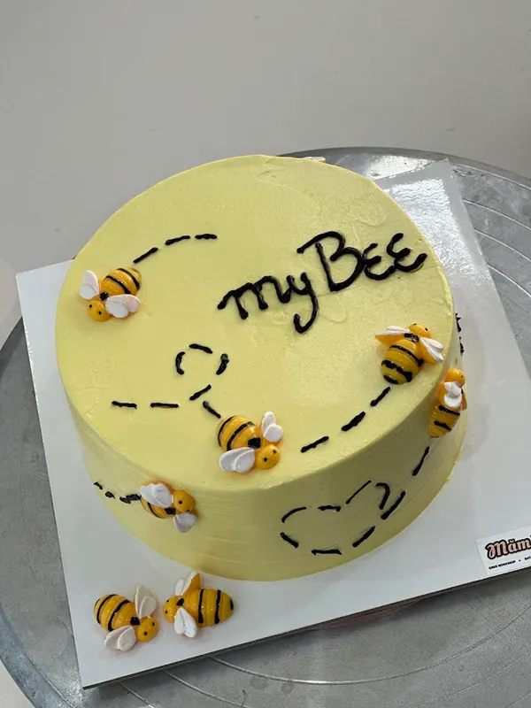 Bánh kem màu vàng trang trí hình những chú ong và dòng chữ “My Bee”.