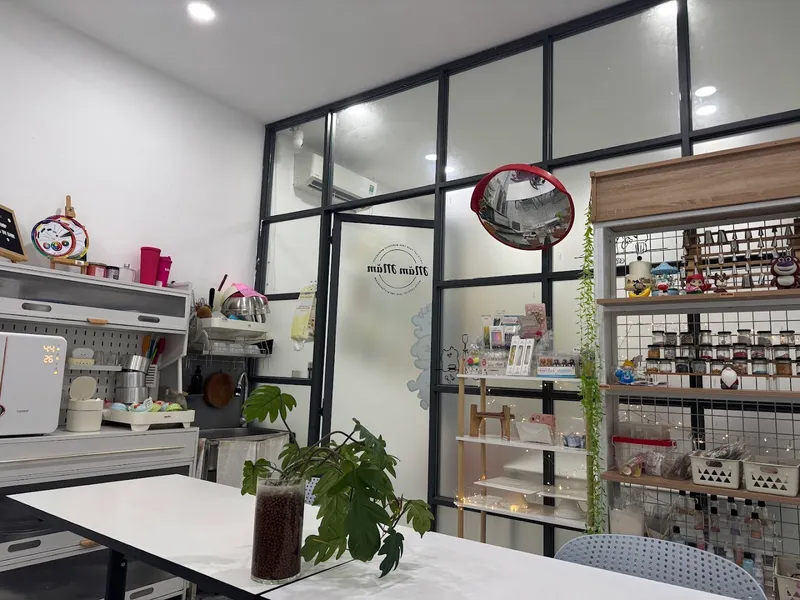 Không gian workshop làm bánh với bàn thực hành, dụng cụ bếp và kệ vật liệu trang trí.