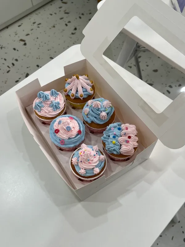 Hộp sáu bánh cupcake trang trí kem màu hồng và xanh pastel.