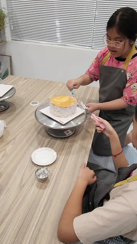 Bánh kem đang được trang trí trên bàn xoay.