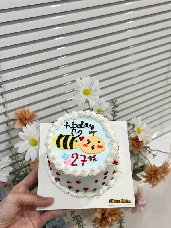 Bánh kem tạo hình ong và nhân vật hoạt hình, trang trí chữ mừng sinh nhật 27 tuổi.